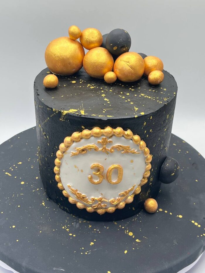 Black and Golden Cake with golden spheres and elegant black buttercream design Black and Golden Cake with golden spheres and elegant black buttercream design